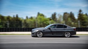A dark gray BMW M5 blasts down a straight on a track.
