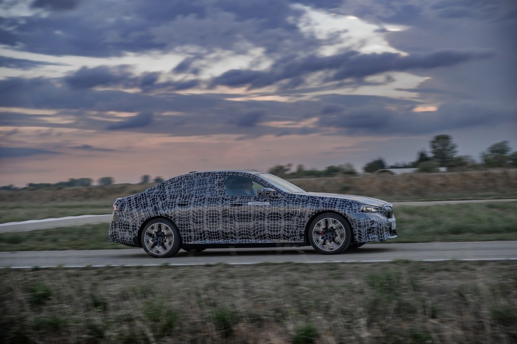 A BMW i5 testing in camouflage paint in the moutnains