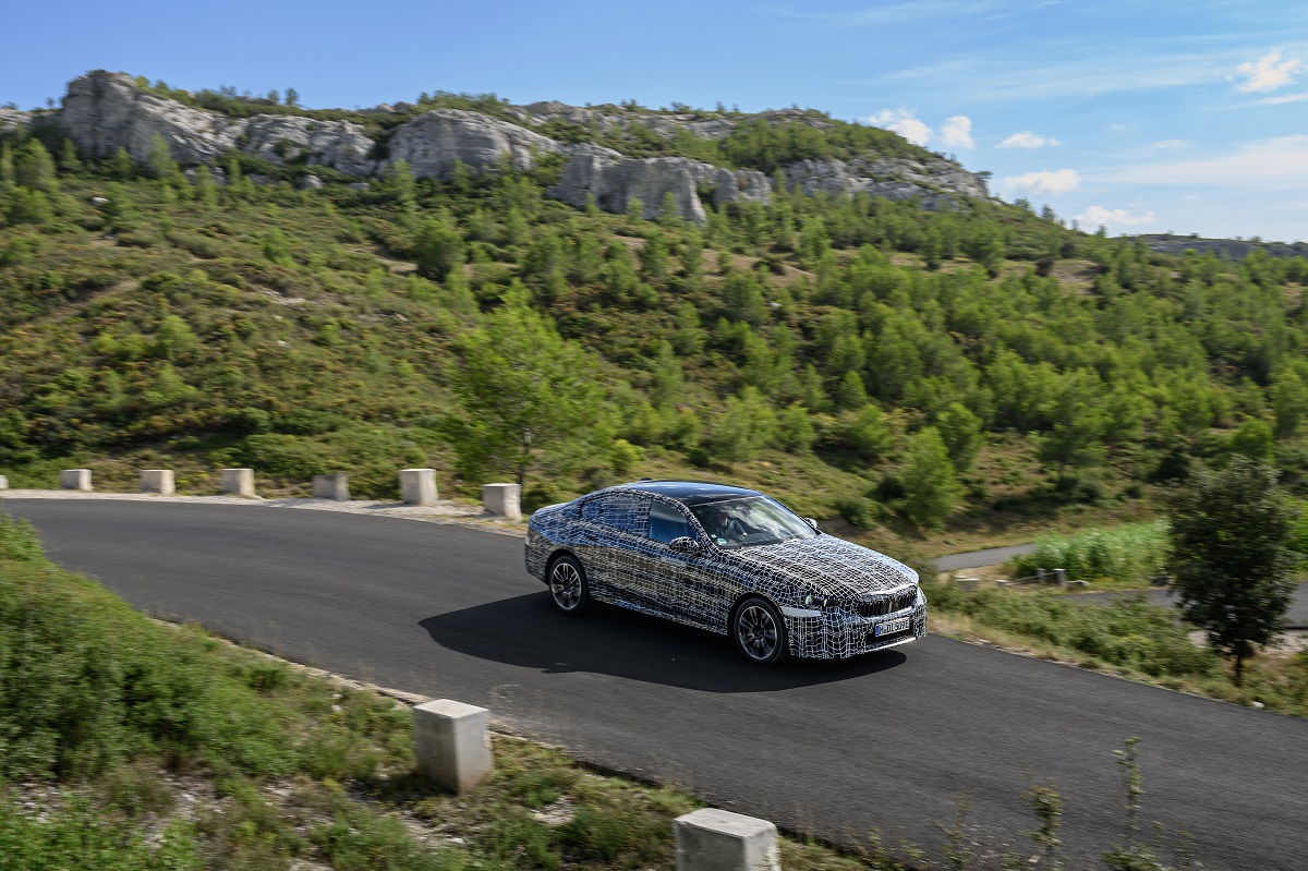 A camouflage BMW i5 on a mountain road