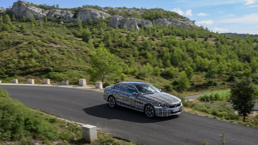 A camouflage BMW i5 on a mountain road
