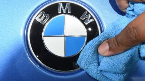 A person wipes a BMW logo with a cloth.