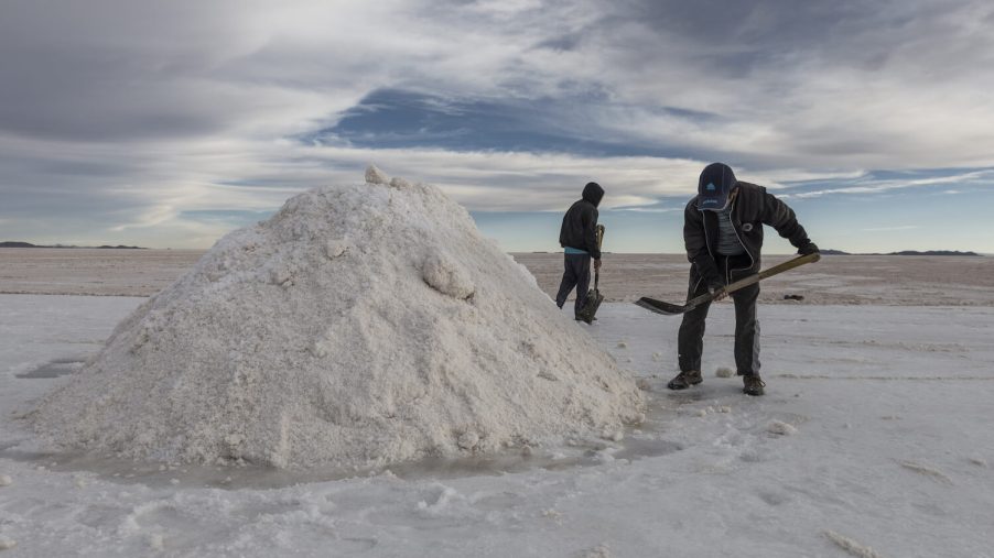 Bolivian lithium production workers shovel salt from the Salar de Uyuni flats to extract the minerals.