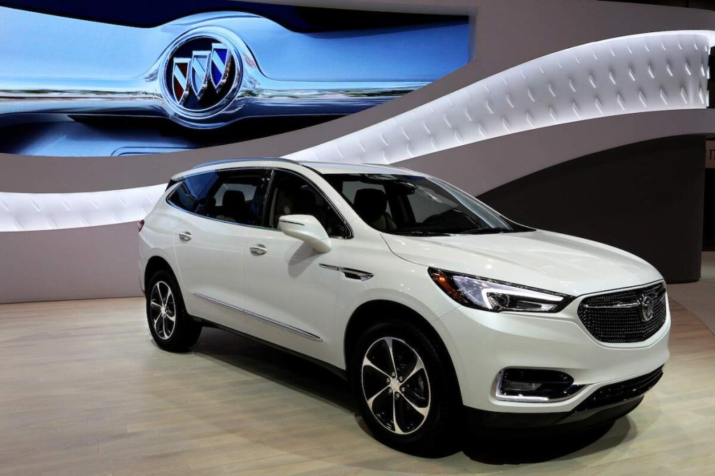 A white Buick Enclave on a beige floor with a white and blue background.