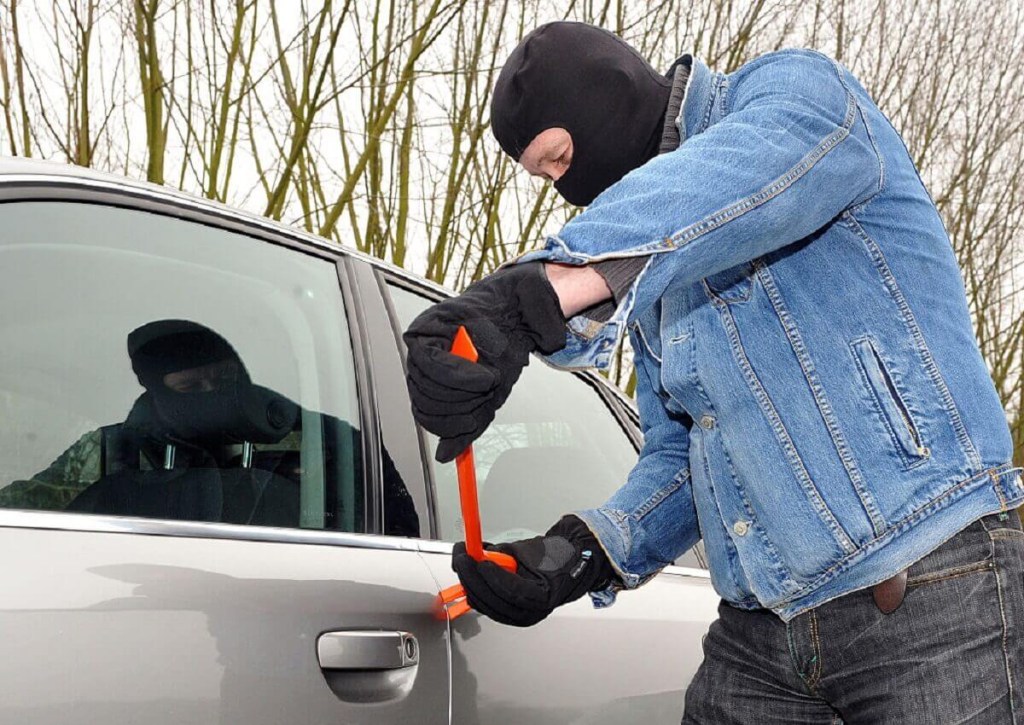 A car thief breaks into a vehicle. Once stolen, a car could get a branded or salvage title.