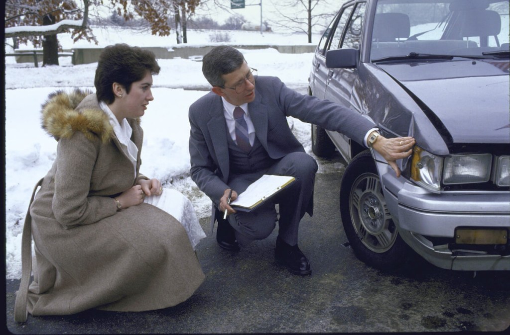 A car insurance agent checks out a driver's car.