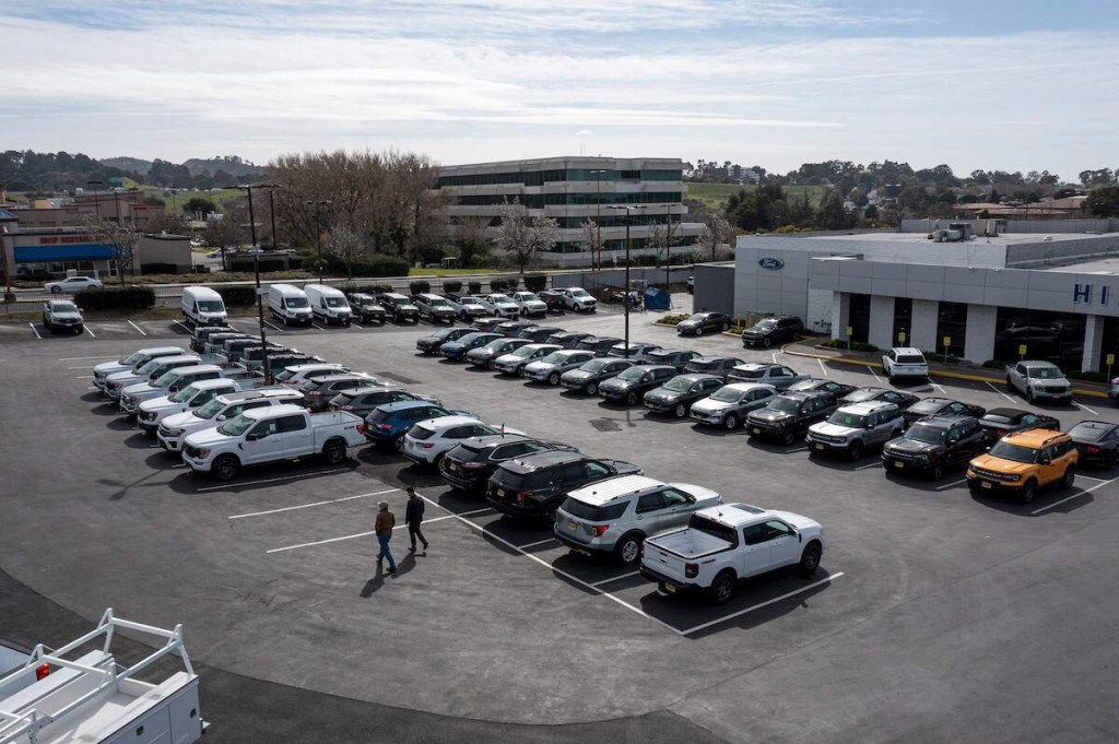 A new car lot, where mechanics could recommend used over new cars, with many options parked across the lot. 
