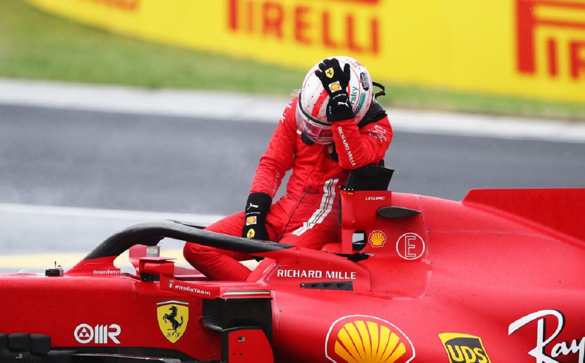 Scuderia Ferrari F1 Driver Charles Leclerc cradles his helmet in his hands.