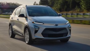 A gray 2023 Chevrolet Bolt EUV subcompact electric SUV is driving on the road.