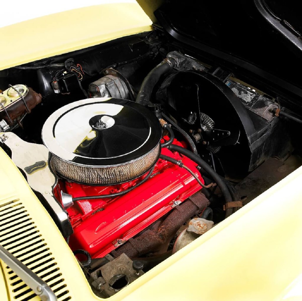 A numbers-matching classic car shows off its VIN tag and small block V8 in an engine bay. 