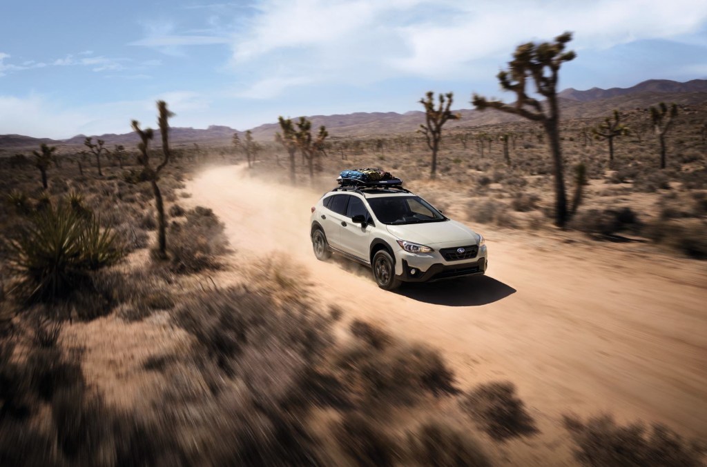 A 2023 Subaru Crosstrek Special Edition drives down a desert road with Joshua Trees and shrubs on either side. 