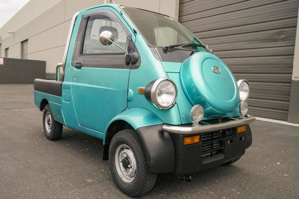 This is a 1996 Daihatsu Midget II compact pickup truck, with a front-mounted spare tire.