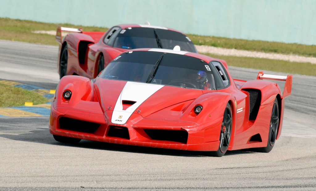 A pair of 2006 Ferrari FXX supercars round a corner on the road course.