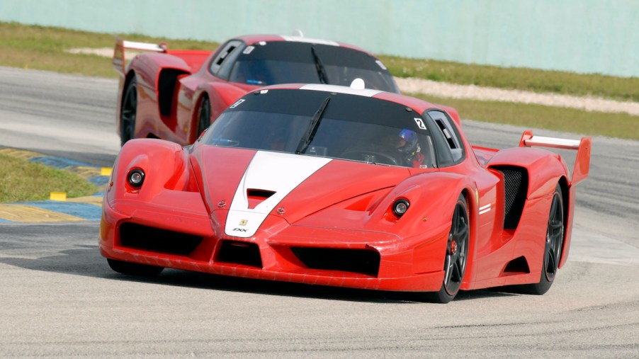 A pair of 2006 Ferrari FXX supercars round a corner on the road course.