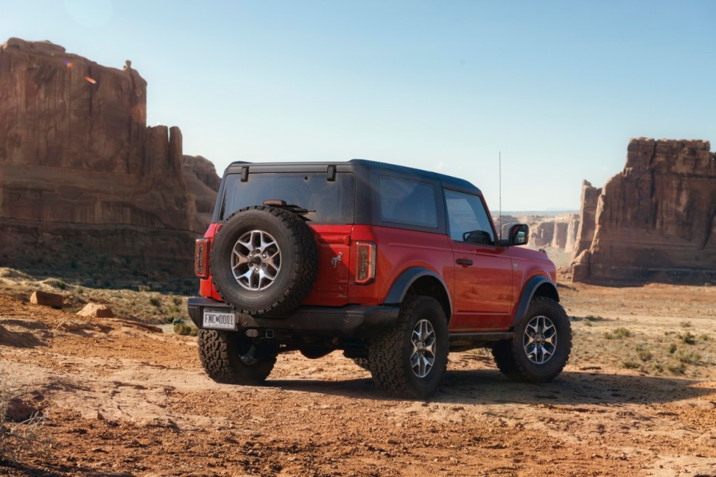 Rear view of a red two-door Ford Bronco sits in a desert landscape. 