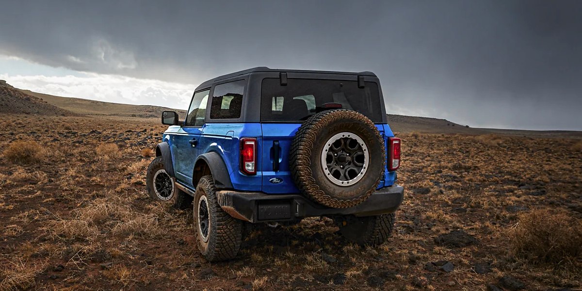 A blue 2023 Ford Bronco midsize SUV is parked off-road.