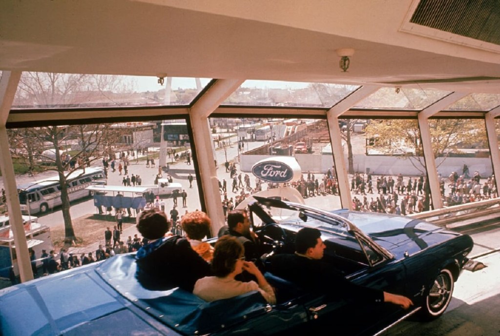 Visitors ride in a convertible 1965 Ford Mustang for the unveiling at the World's Fair. 