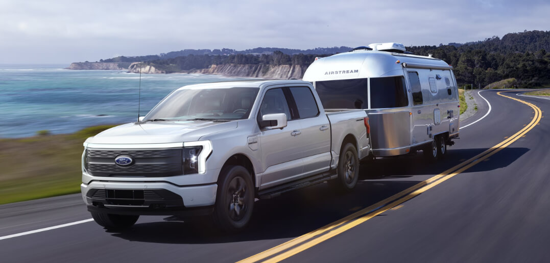 A Ford F-150 Lightning EV tows a trailer.