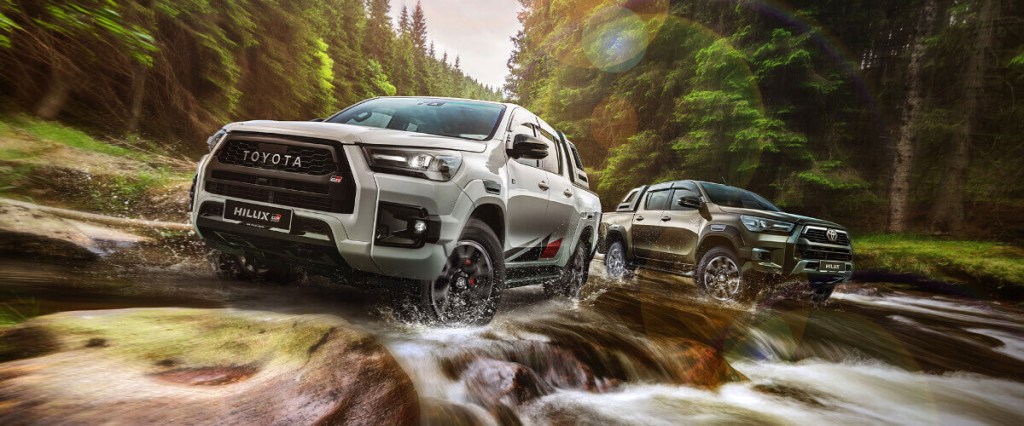 A pair of Toyota Hilux GR Sport midsize trucks driving off-road.