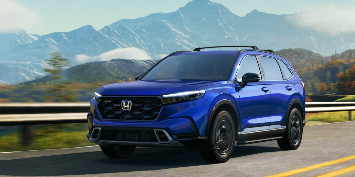 A blue 2023 Honda CR-V small SUV is driving on the road.