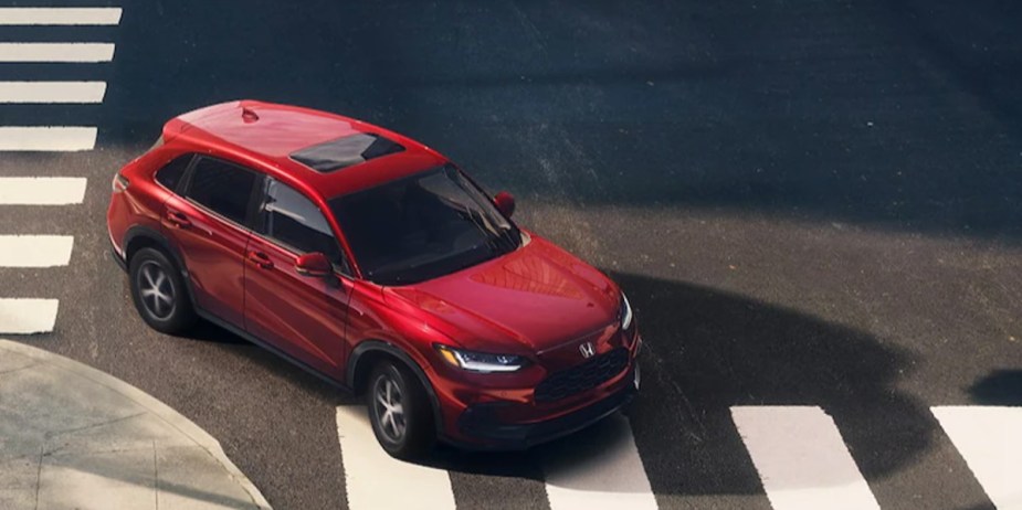 A red 2023 Honda HR-V subcompact SUV is driving on the road. 