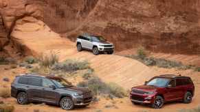 A Jeep Grand Cherokee, Grand Cherokee L, and Grand Cherokee 4xe posed amid desert sandstone formations.