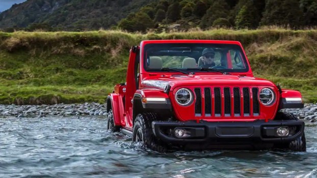 A Jeep Wrangler driving across a river.