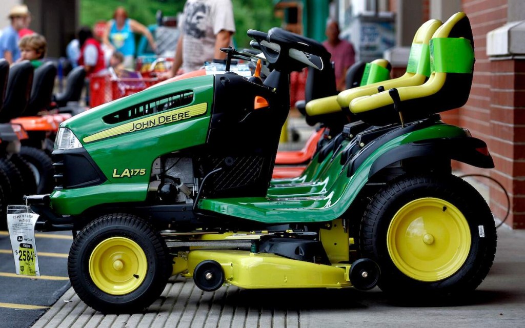 A green John Deere lawn mower parked outdoors that the owner may need to know how to charge a riding lawn mower battery during ownership. 