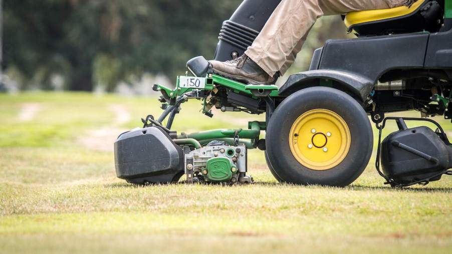 A person driving a lawn mower, which could have an issue so it is important to know common lawn mower problems.