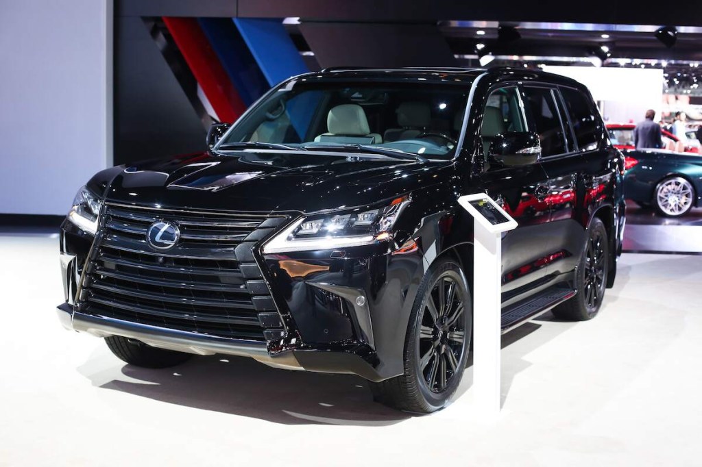A black Lexus LX 570 parked on a white floor with a dark background.