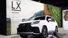 A white Lexus LX 600 in front of a white and green background.
