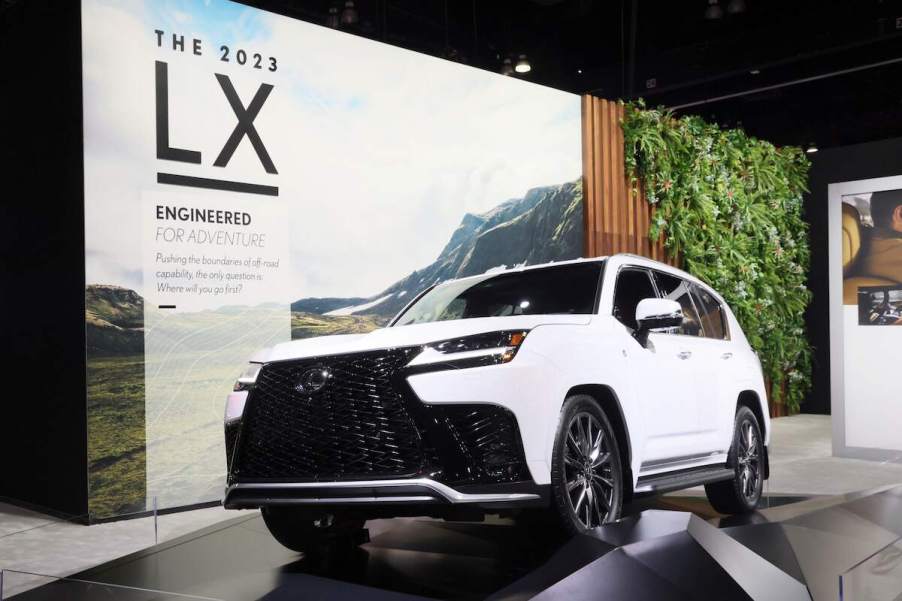 A white Lexus LX 600 in front of a white and green background.
