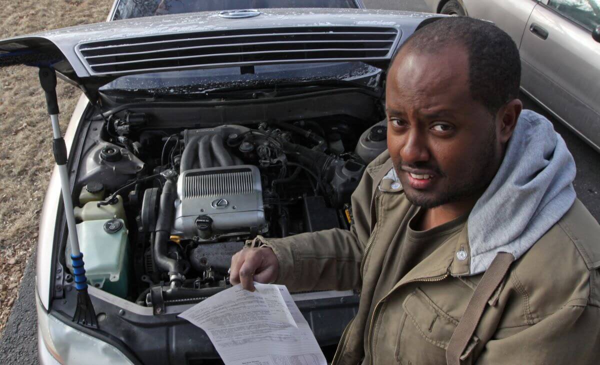 Yonas Bekele showing off fire damage to his 1993 Lexus car that happened during a routine oil change
