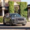 A new Lincoln Aviator its in front a luxury home covered in ivy.