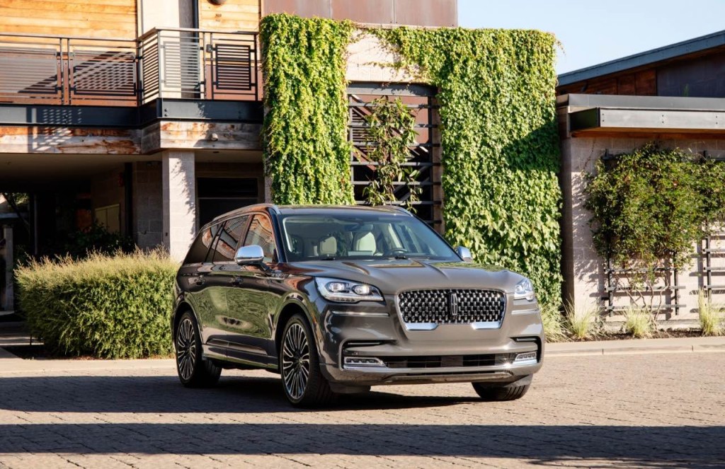A new Lincoln Aviator its in front a luxury home covered in ivy. 