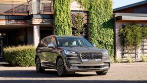 A new Lincoln Aviator its in front a luxury home covered in ivy.