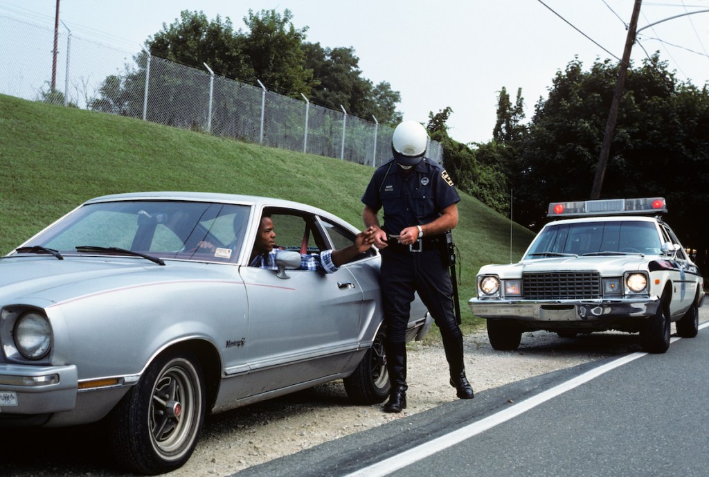 1970s POLICE OFFICER pulling a guy over in an old car