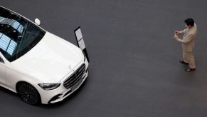 A man takes a picture of a Mercedes C-Class luxury car at an auto show.