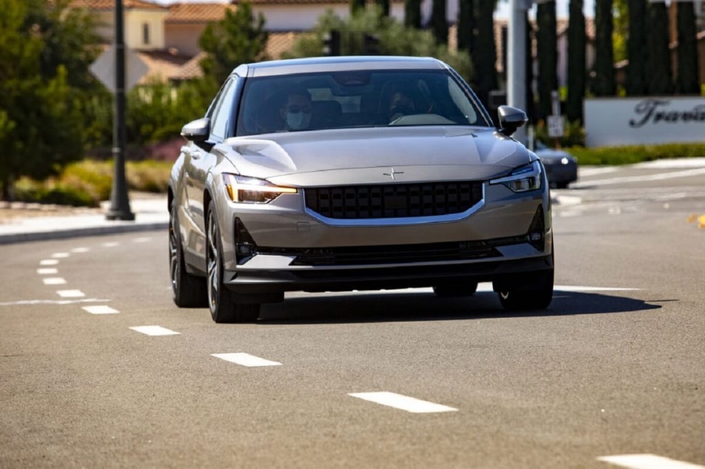 A champagne Polestar 2 shows off its Tesla Model 3-challenging proportions on a city street.