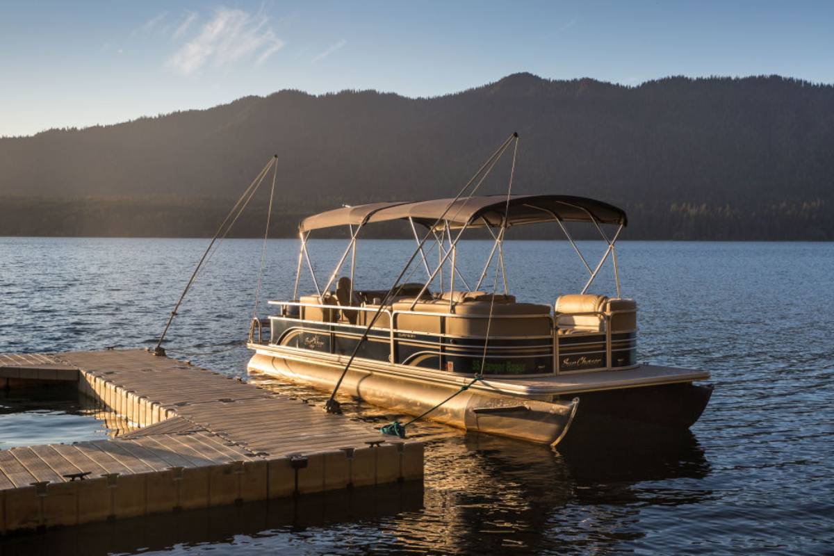 A pontoon boat tied up on a floating dock.