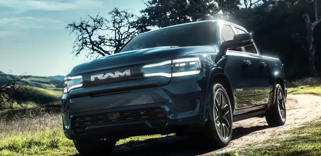 The Ram 1500 REV electric truck drives on a dirt road.
