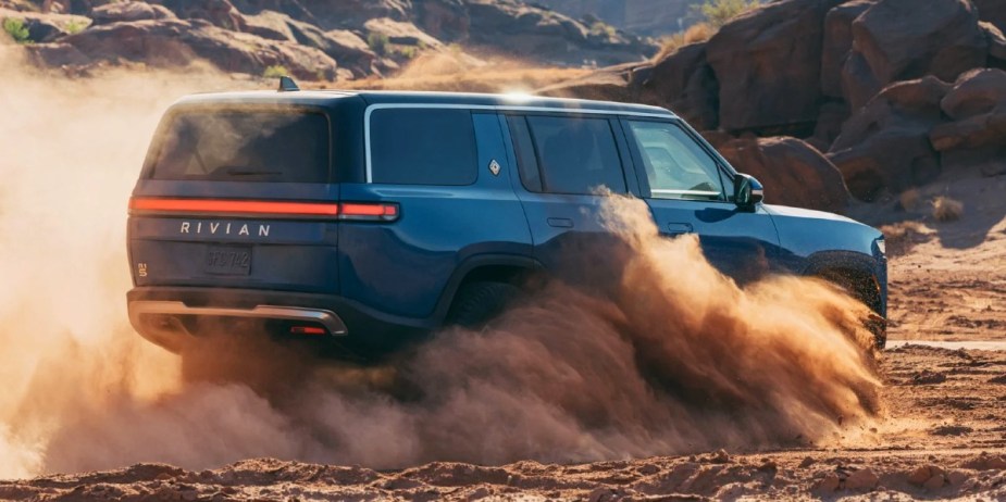 A blue 2023 Rivian R1S is off-roading in the sand. 