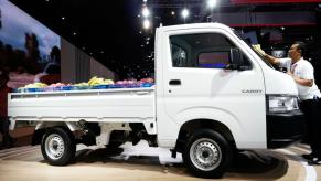 A Suzuki Carry mini-truck is on display at an auto show.