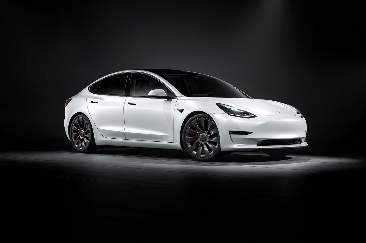 A white Tesla Model 3 waits to head to a test drive hub while soaking up overhead lights.