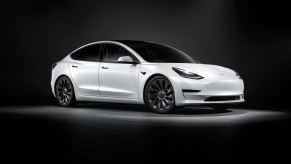 A white Tesla Model 3 waits to head to a test drive hub while soaking up overhead lights.