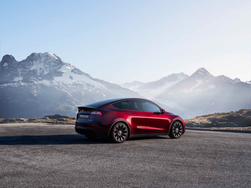 A red Tesla Model Y with mountains in the background. 