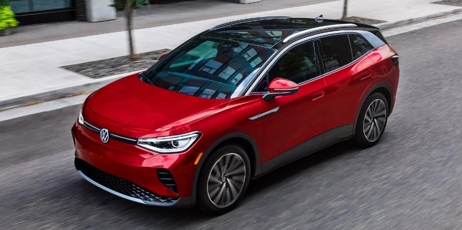 A red 2023 Volkswagen ID.4 small electric SUV is driving on the road. 