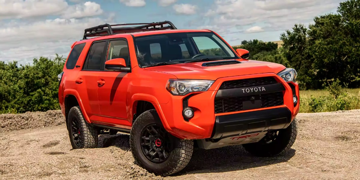 An orange Toyota 4Runner midsize SUV is parked off-road.