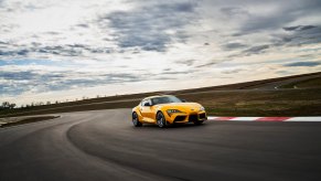 A bright yellow Toyota GR Supra 2.0 takes a corner on a track.