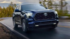 A blue 2023 Toyota Sequoia full-size SUV is driving on the road.