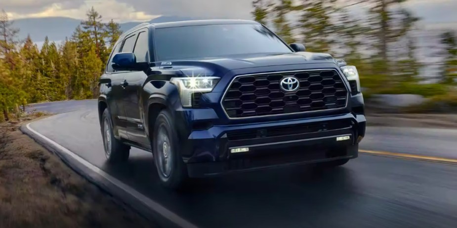 A blue Toyota Sequoia full-size SUV is driving on the road. 